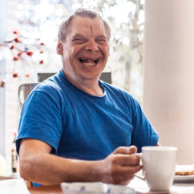 Man smiling and enjoying a cuppa - As I Am | DPCN - Disability Participation and Consultation Network