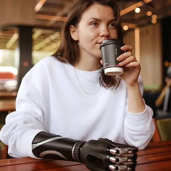 Woman with a prosthetic arm drinking a beverage - Disabled Women Ireland | DPCN - Disability Participation and Consultation Network